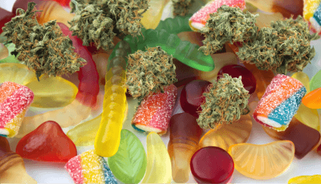 Gummies and fruits arranged beside cannabis flower.
